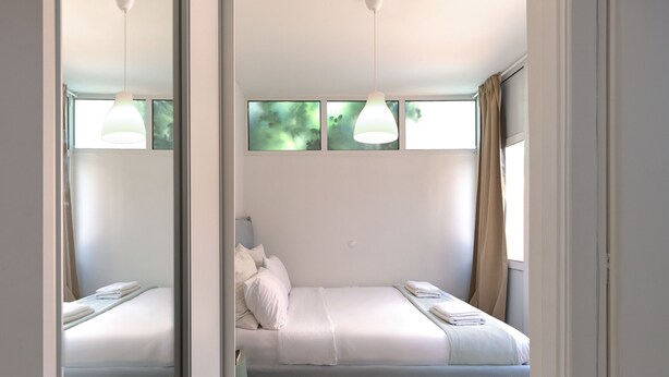 A modern bedroom with a bed, bedside tables, and a window with curtains. - Cozy Garden Studio (Athens)
