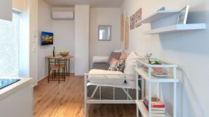 A compact living space with a bed, a dining area, and a TV. - Cozy Garden Studio (Athens)