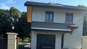 Une maison à deux étages avec un garage, une allée et une entrée fermée par un portail.