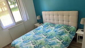 Une chambre à coucher avec un lit, une fenêtre, une table de chevet et une lampe.