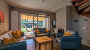 A modern living room with a sofa set, a coffee table, and a TV. - Abbestederweg 24A holiday home in Callanstoog (Callantsoog)