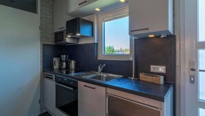 A modern kitchen with a built-in oven, a microwave, a coffee maker, and a window above the sink. - Abbestederweg 24A holiday home in Callanstoog (Callantsoog)