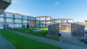 A courtyard with a playground, a covered seating area, and a building with multiple balconies.