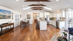 A spacious kitchen with white cabinets, a central island, and a stainless steel refrigerator. - Rooftop Retreat - Monterey House - Walk to the Monterey Aquarium (Monterey)