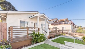 Une maison à deux étages dotée d’un balcon, d’une terrasse en bois et d’une pelouse bien entretenue.