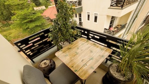 Ein Balkon mit Holztisch und zwei grauen Stühlen, umgeben von Blumentöpfen.