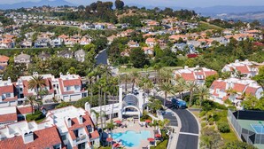 A residential area with a swimming pool, houses with red roofs, and palm trees. - Encantamar Escape by AvantStay | Prime Location + Community Amenities (Dana Point)