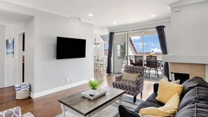 A modern living room with a flat-screen TV, a fireplace, and a dining area with a view. - Encantamar Escape by AvantStay | Prime Location + Community Amenities (Dana Point)