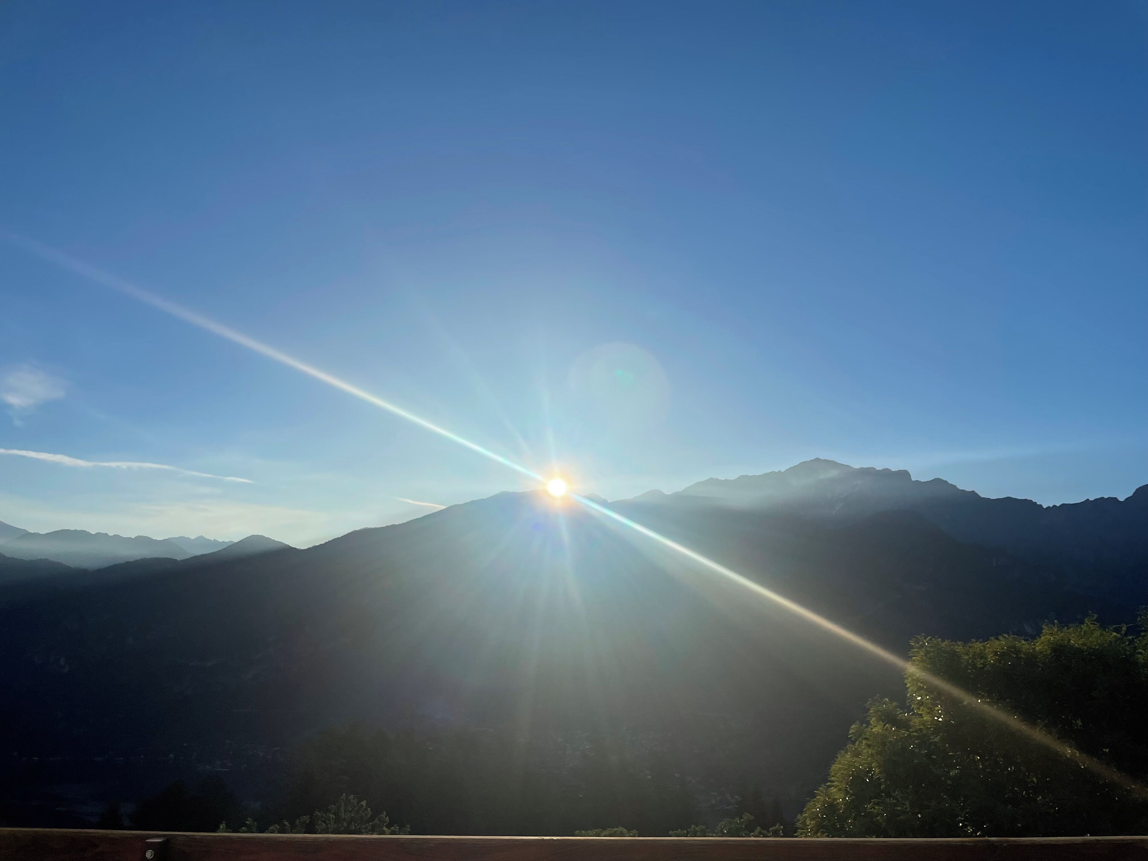 Paisaje de montaña con cielo despejado y el sol brillando intensamente.