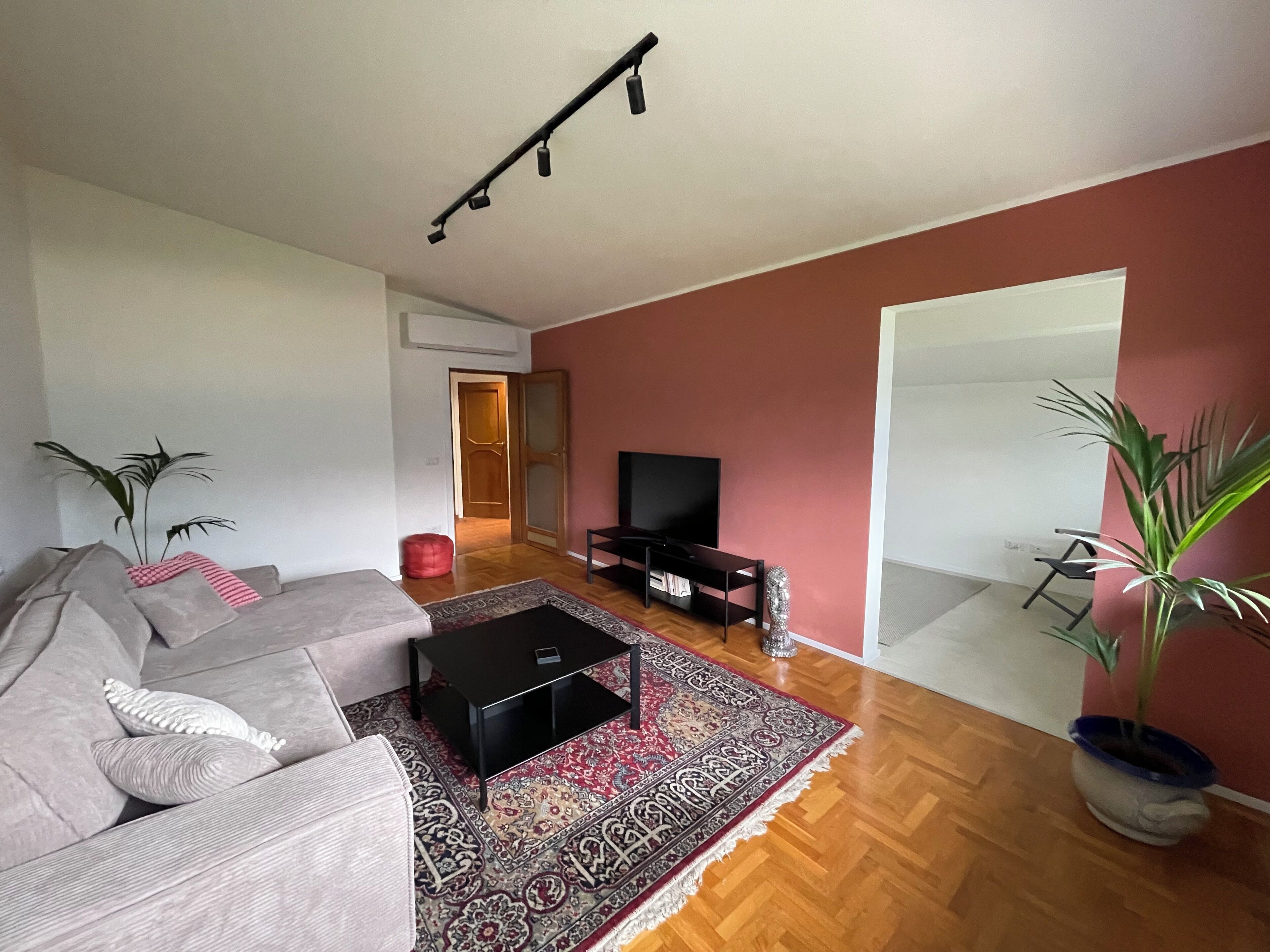 Sala de estar con sofá, mesa de centro, televisor y una pared de acento roja.