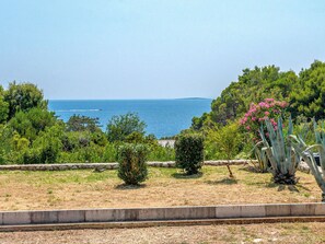 A coastal landscape with a clear view of the sea, a stone pathway, and various shrubs and trees. - Dundo House by Interhome (Rab/Kampor)
