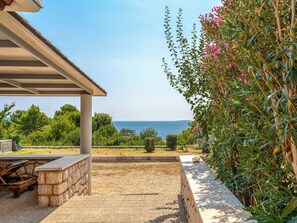 A patio with a stone bench, a pergola, and a view of the sea.