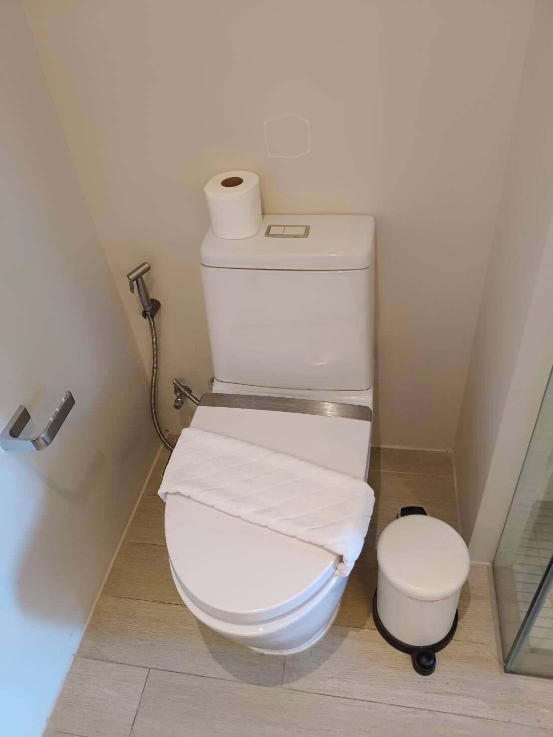 A compact bathroom with a toilet, bidet, and a small trash bin.