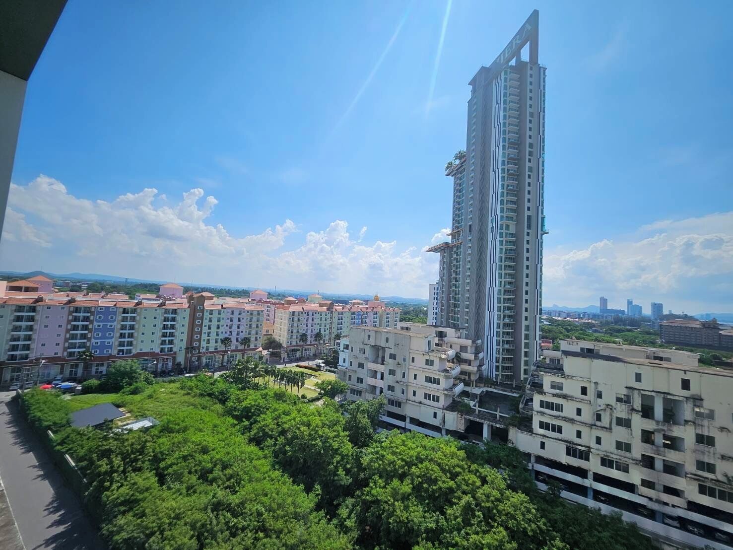 A high-rise building with a modern design, surrounded by other residential buildings and greenery.
