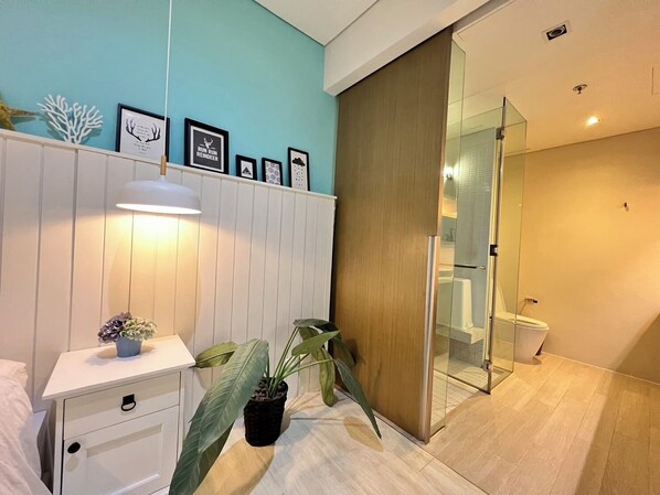 A modern bathroom with a glass shower enclosure, a white vanity with a lamp, and a potted plant. - Residence Veranda By Thita (Pattaya)