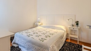 Ein ordentlich eingerichtetes Schlafzimmer mit Bett, Nachttischen und einem Beistelltisch.