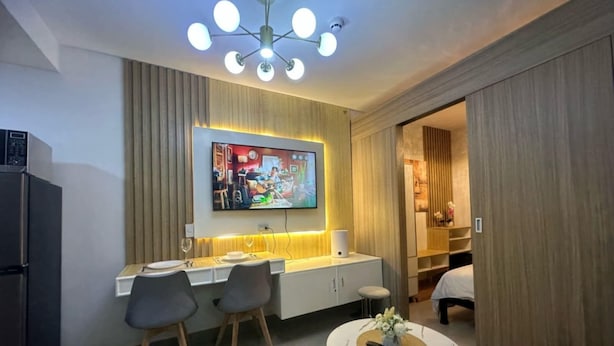 A modern living room with a dining area, a TV mounted on the wall, and a ceiling light fixture. - Chic 1-bedroom apartment in brilliant Pasay with WiFi, AC (philippines)