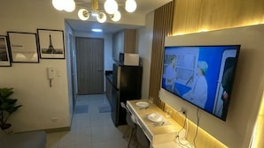 A modern kitchen with a dining area, a TV mounted on the wall, and a ceiling light fixture. - Chic 1-bedroom apartment in brilliant Pasay with WiFi, AC (philippines)
