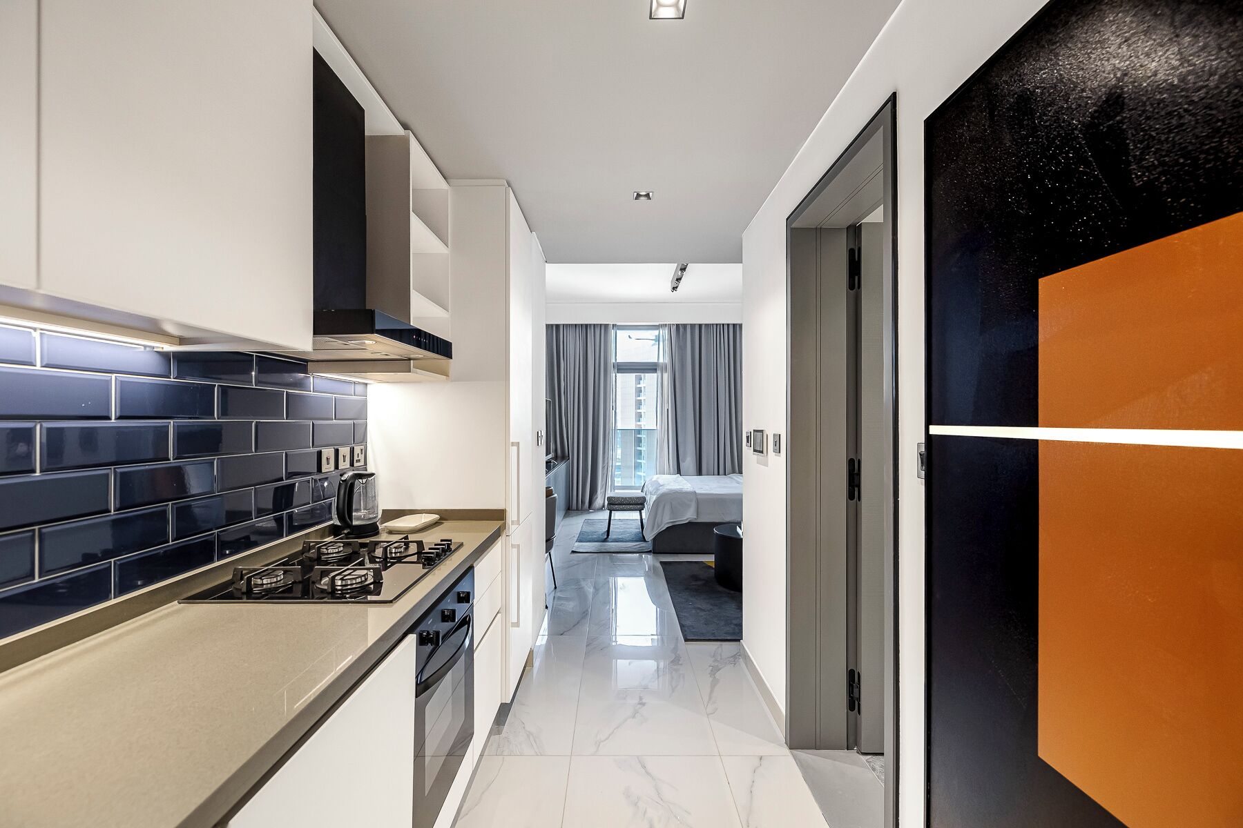 A modern kitchen with a gas stove, a coffee maker, and a tiled backsplash.