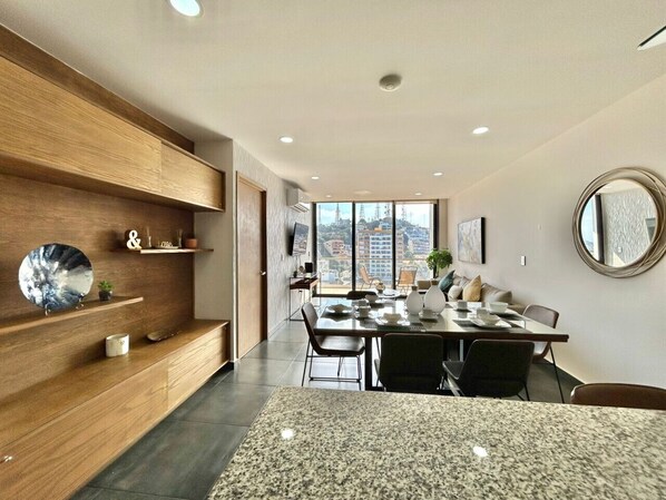 Un comedor moderno con encimera de granito, estanterías de madera y un amplio ventanal con vistas a la ciudad.
