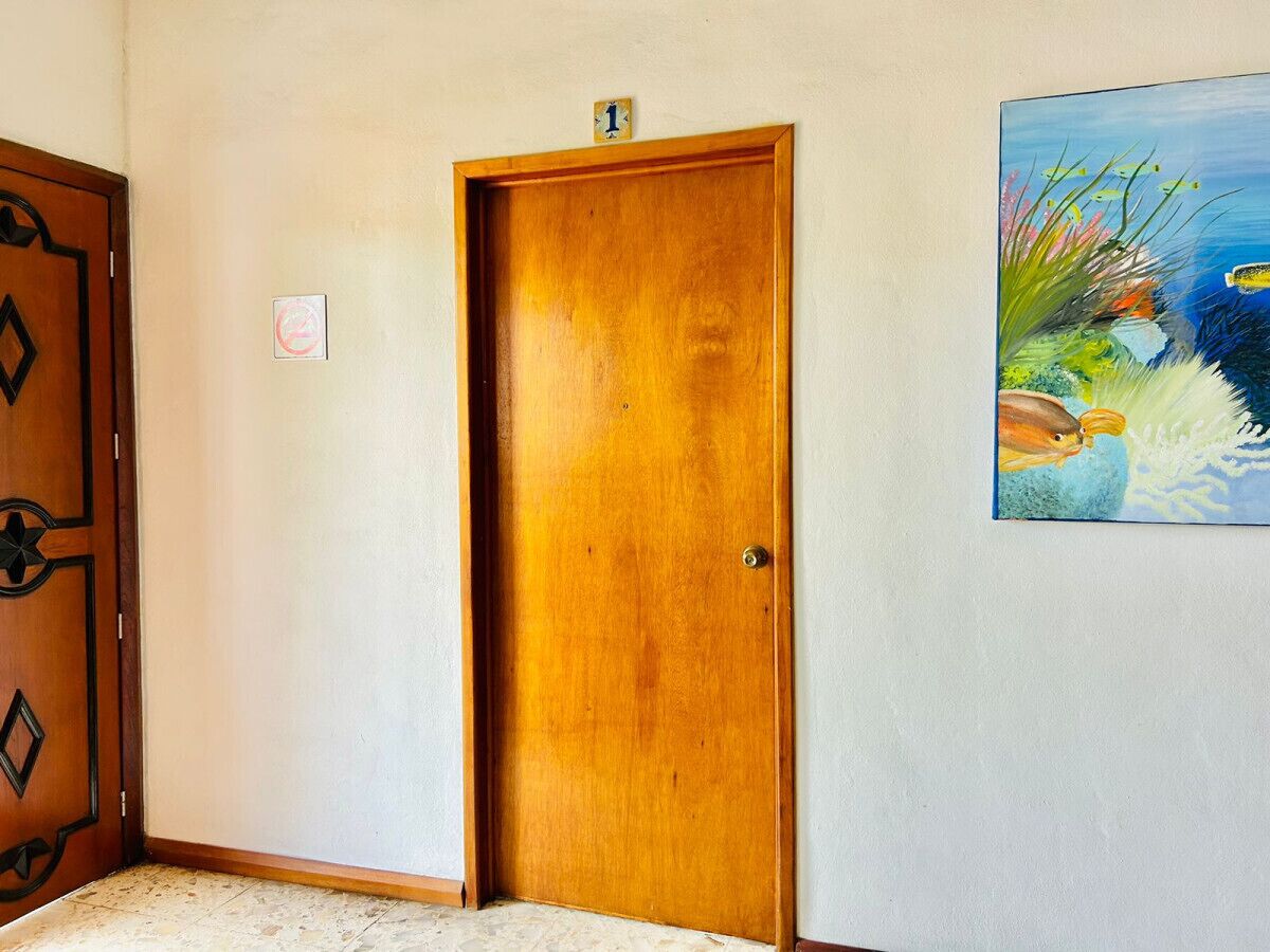 Eine Holztür mit einem kleinen Schild darüber, einem Gemälde an der Wand und einem Teppichboden.