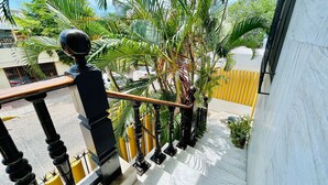 Een balkon met een zwarte balustrade, witte marmeren treden en weelderige groene palmstruiken.