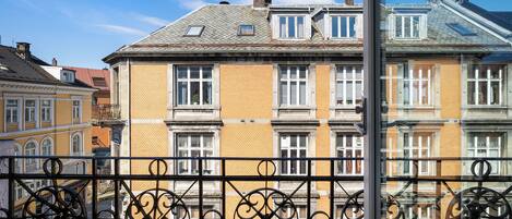 Un edificio con varias ventanas y un balcón con barandilla de metal decorativa.