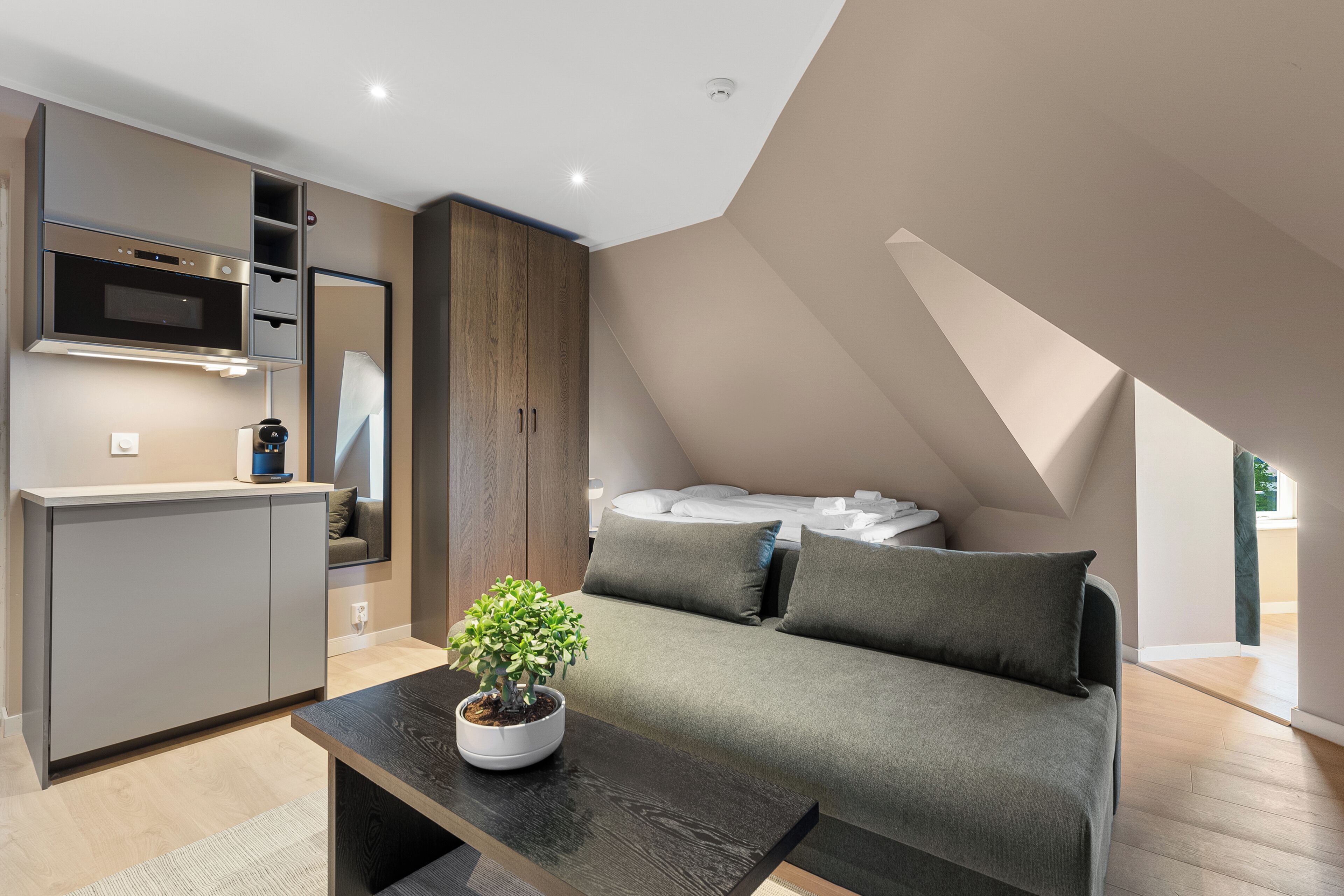 Un dormitorio moderno estilo loft con cama empotrada, kitchenette y zona de comedor.