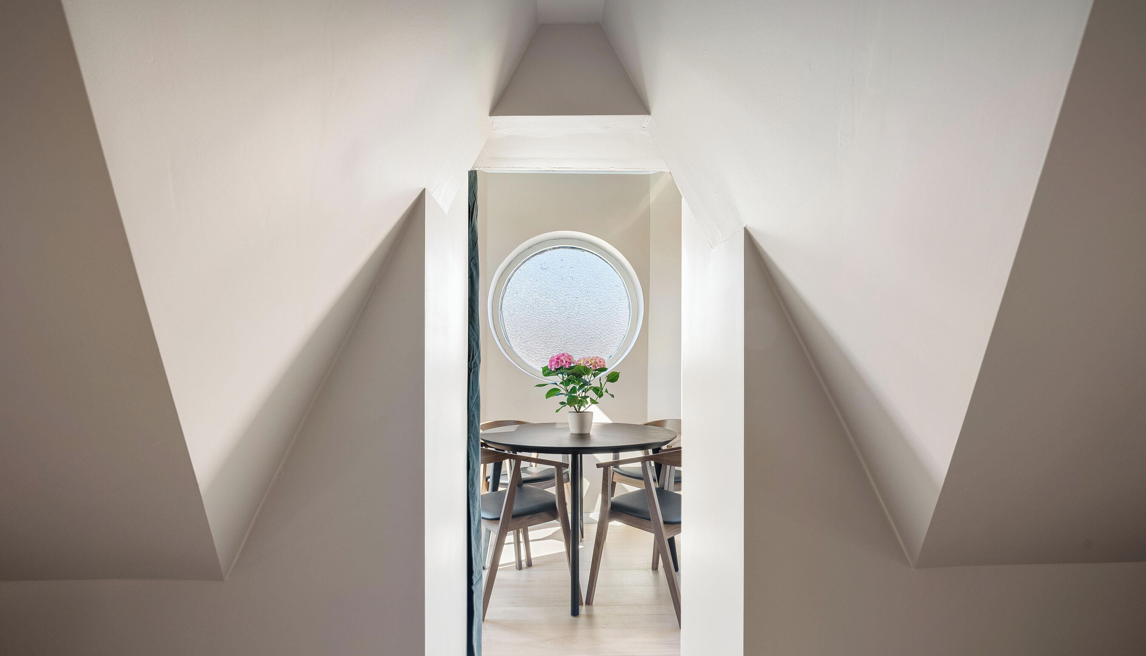 A room with a skylight, a round table, and four chairs.