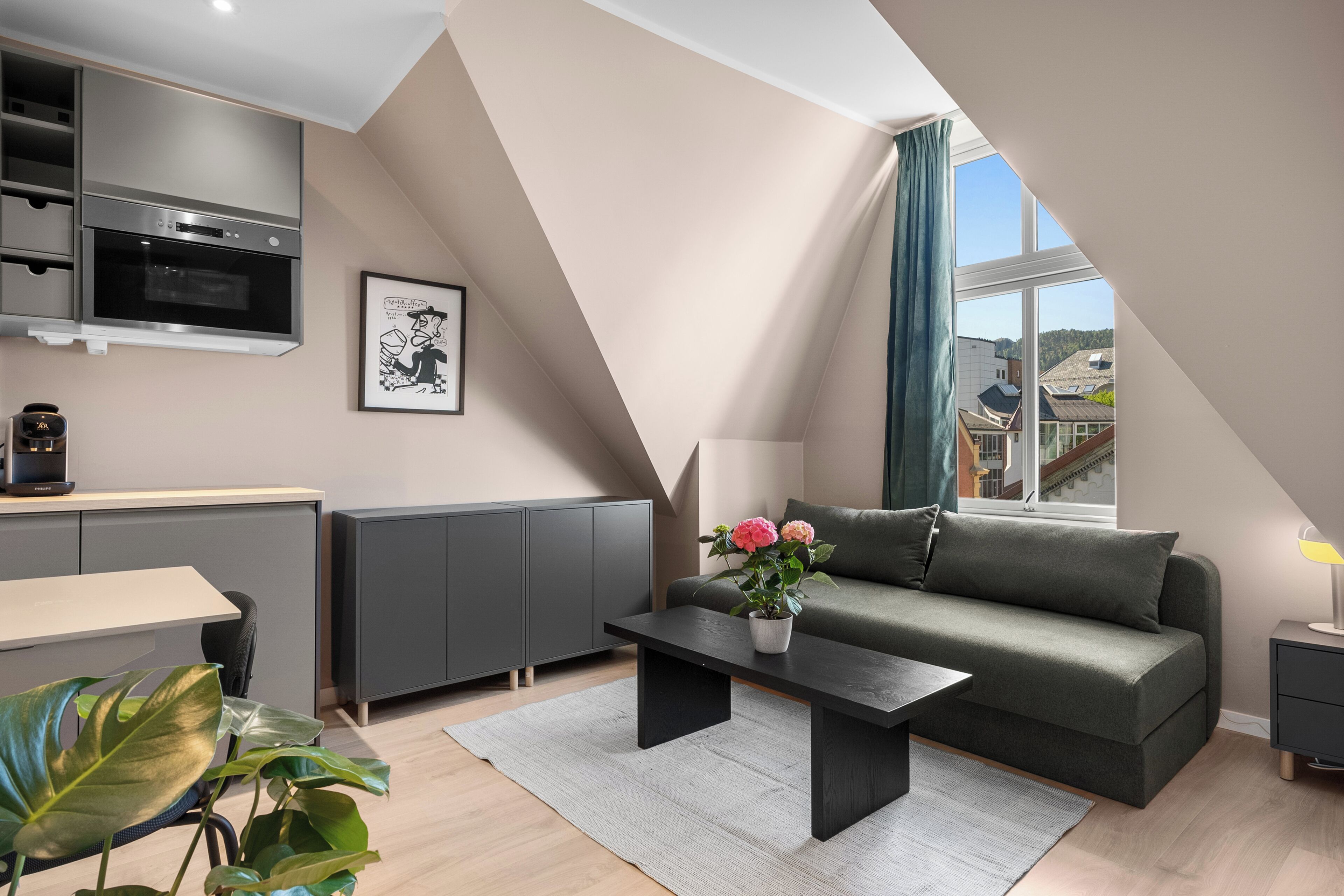 A modern loft-style living space with a kitchen, a sofa, a coffee table, and a view of the outside.