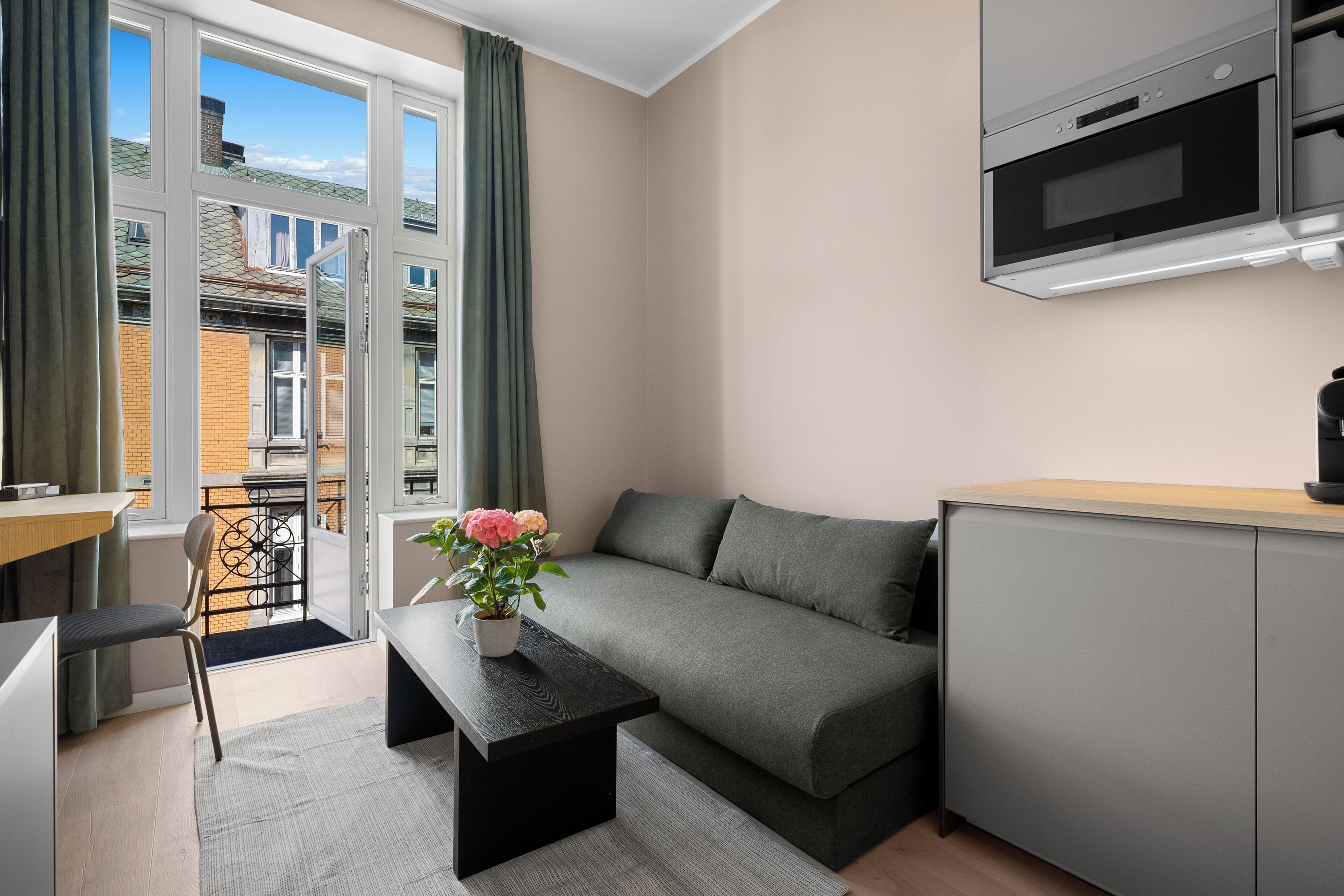 A compact living space with a kitchenette, a sofa, a dining area, and a view of the outside.