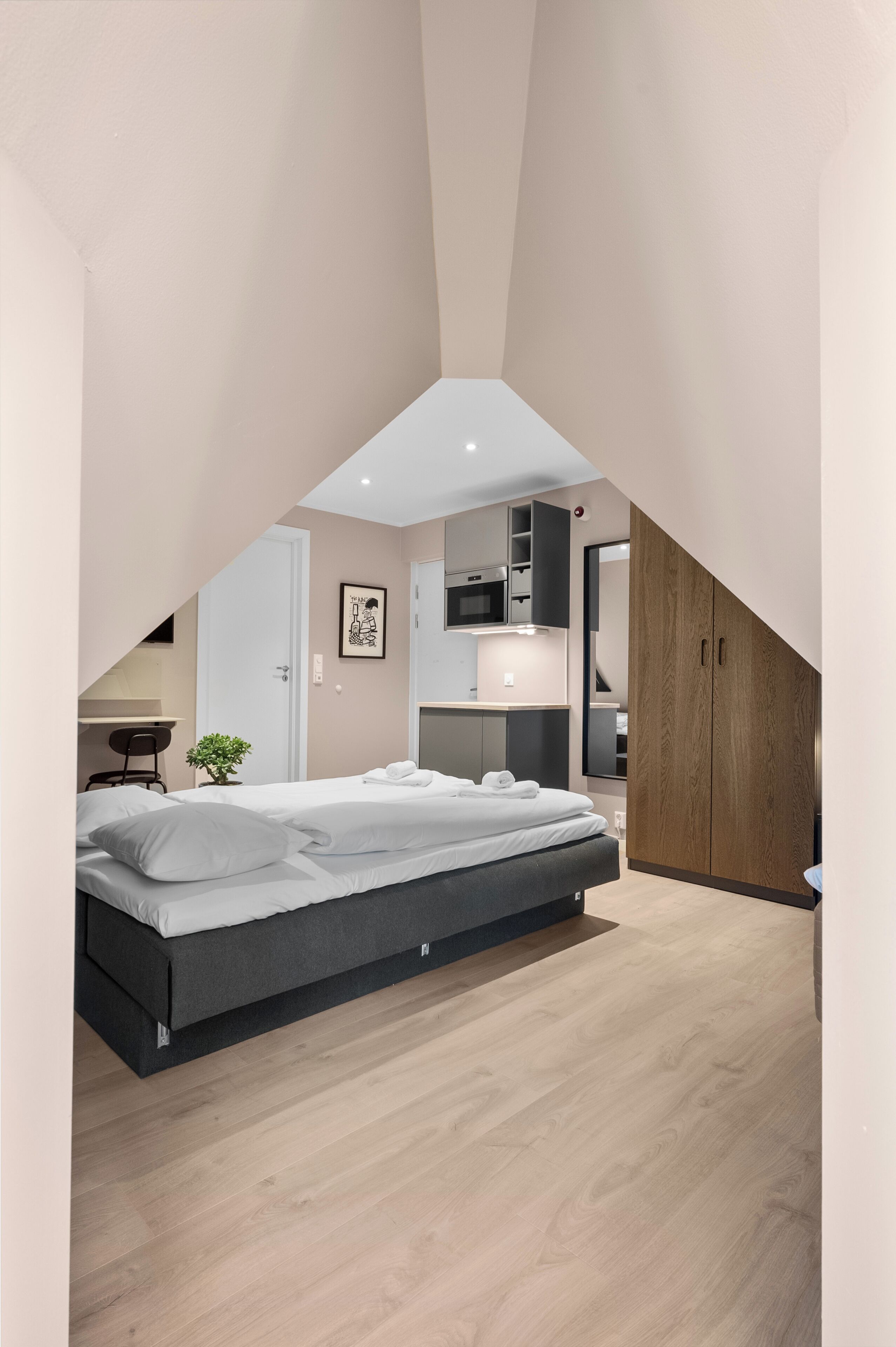 Un dormitorio tipo loft moderno con cama, escritorio y kitchenette.