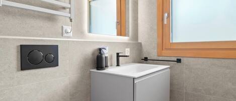 A modern bathroom with a toilet, sink, and window.