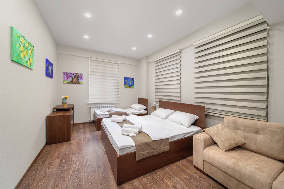 Una habitación de hotel moderna con una cama grande, un sofá y una mesita con un florero.