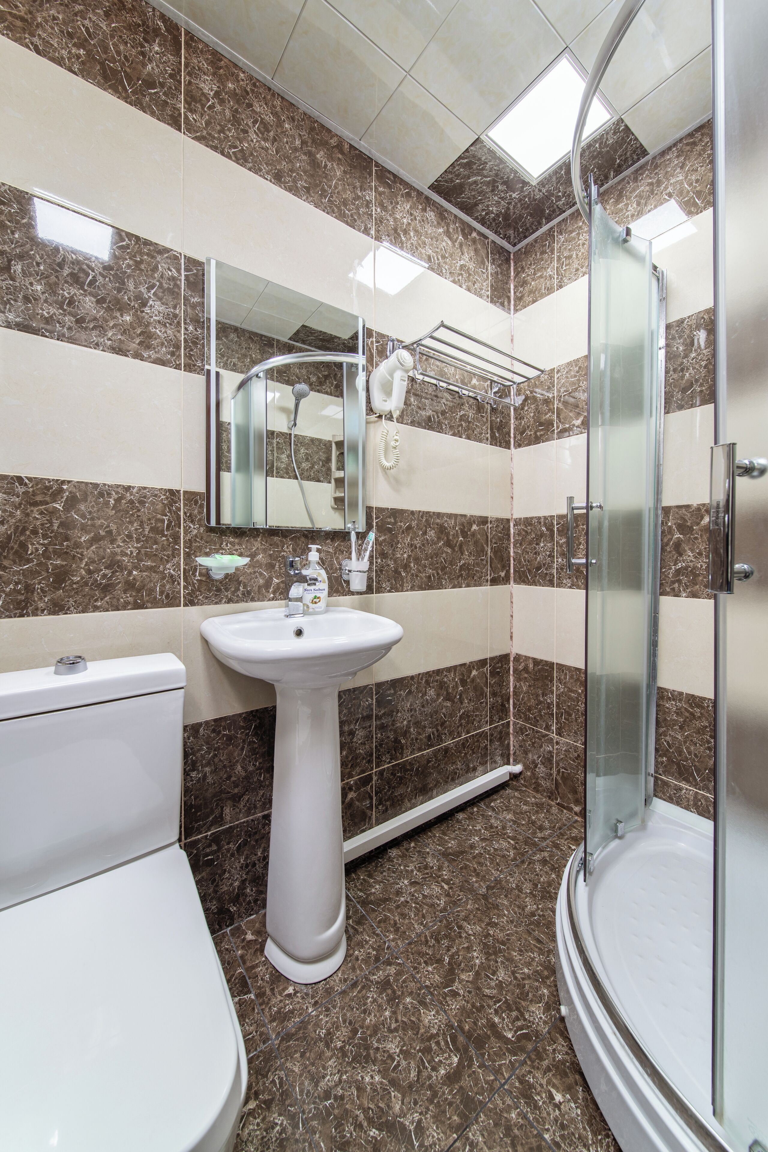 Un baño con inodoro, lavamanos y cabina de ducha con paredes de vidrio.