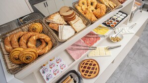 Un bufé con panes, pasteles, quesos y untables varios.