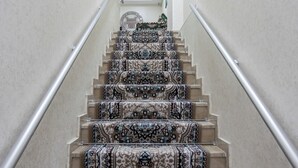 Una escalera con alfombra estampada y barandilla de metal.