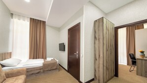Una habitación de hotel con cama, sofá, escritorio y armario.