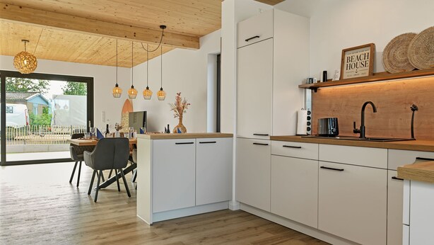 A modern kitchen with white cabinets, a wooden countertop, and pendant lights. - Great newly built house close to the beach (Insel Poel)