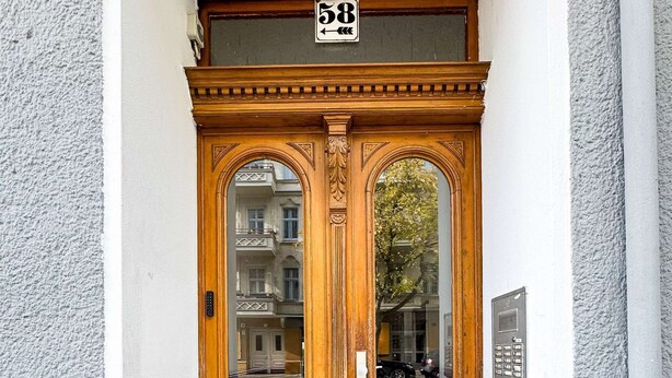 Puerta doble de madera con el número "58" sobre ella, en una pared blanca con textura.