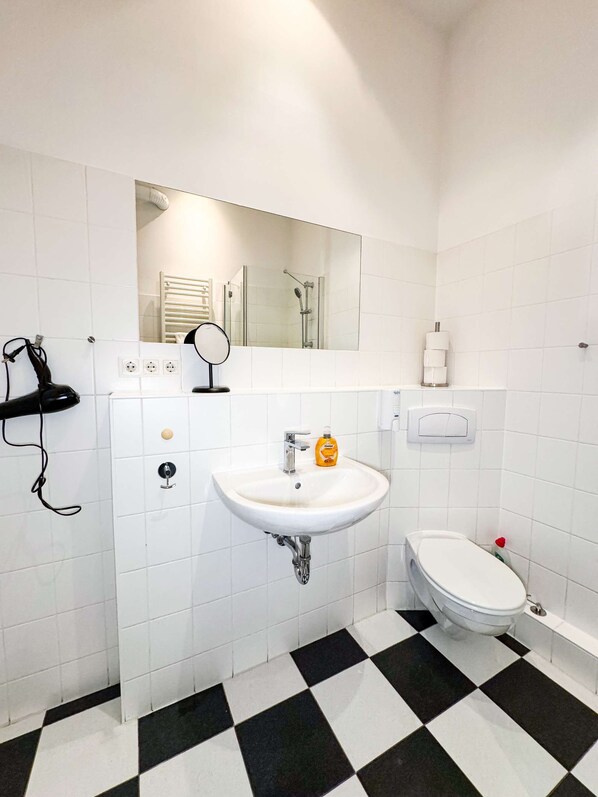 Une salle de bain avec un lavabo blanc, des toilettes et un miroir au-dessus du lavabo.