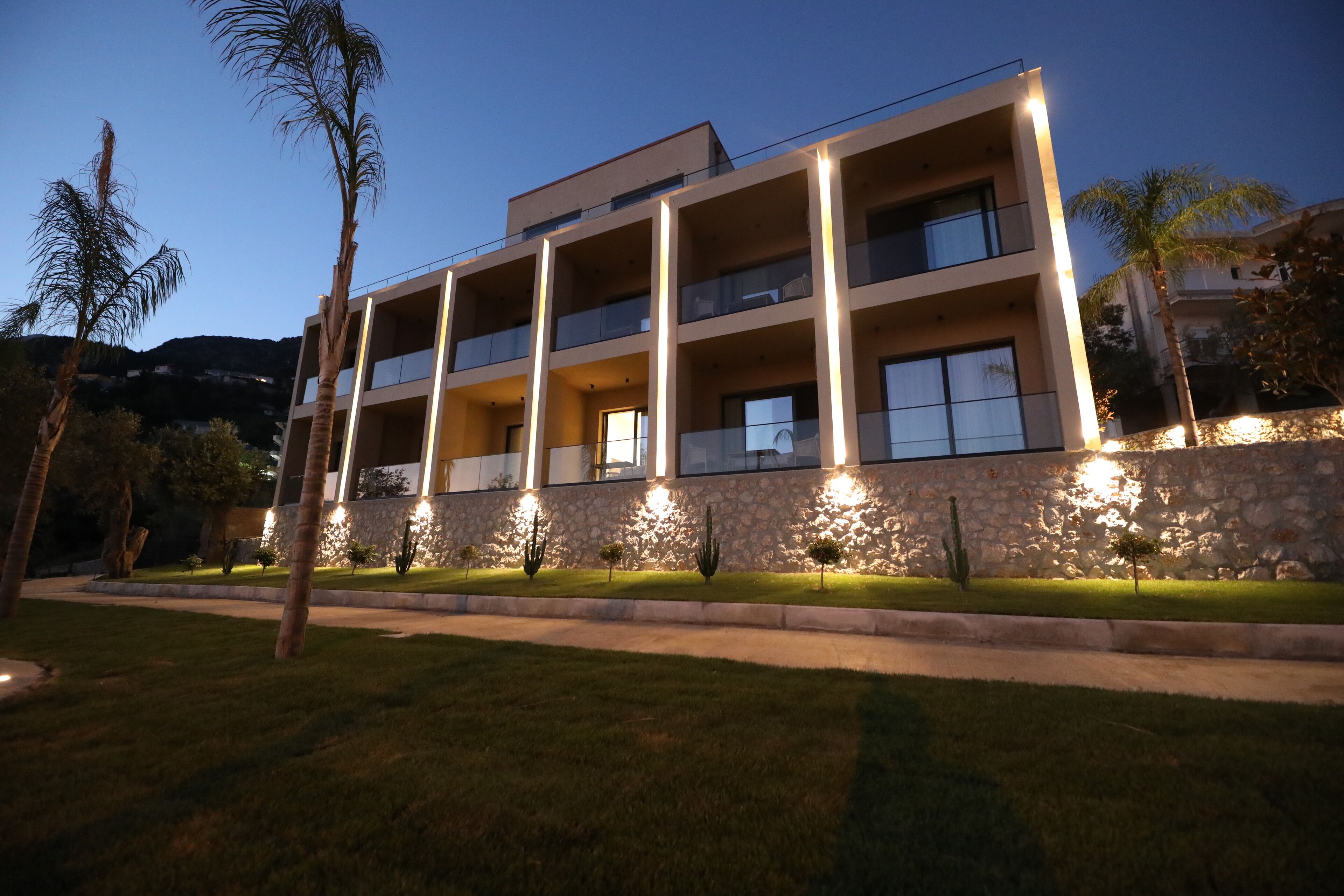 A multi-story building with balconies, a stone facade, and a well-lit entrance.