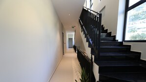 A modern interior with a staircase, a potted plant, and a view through a window. - Aurum Hotel (Himarë)