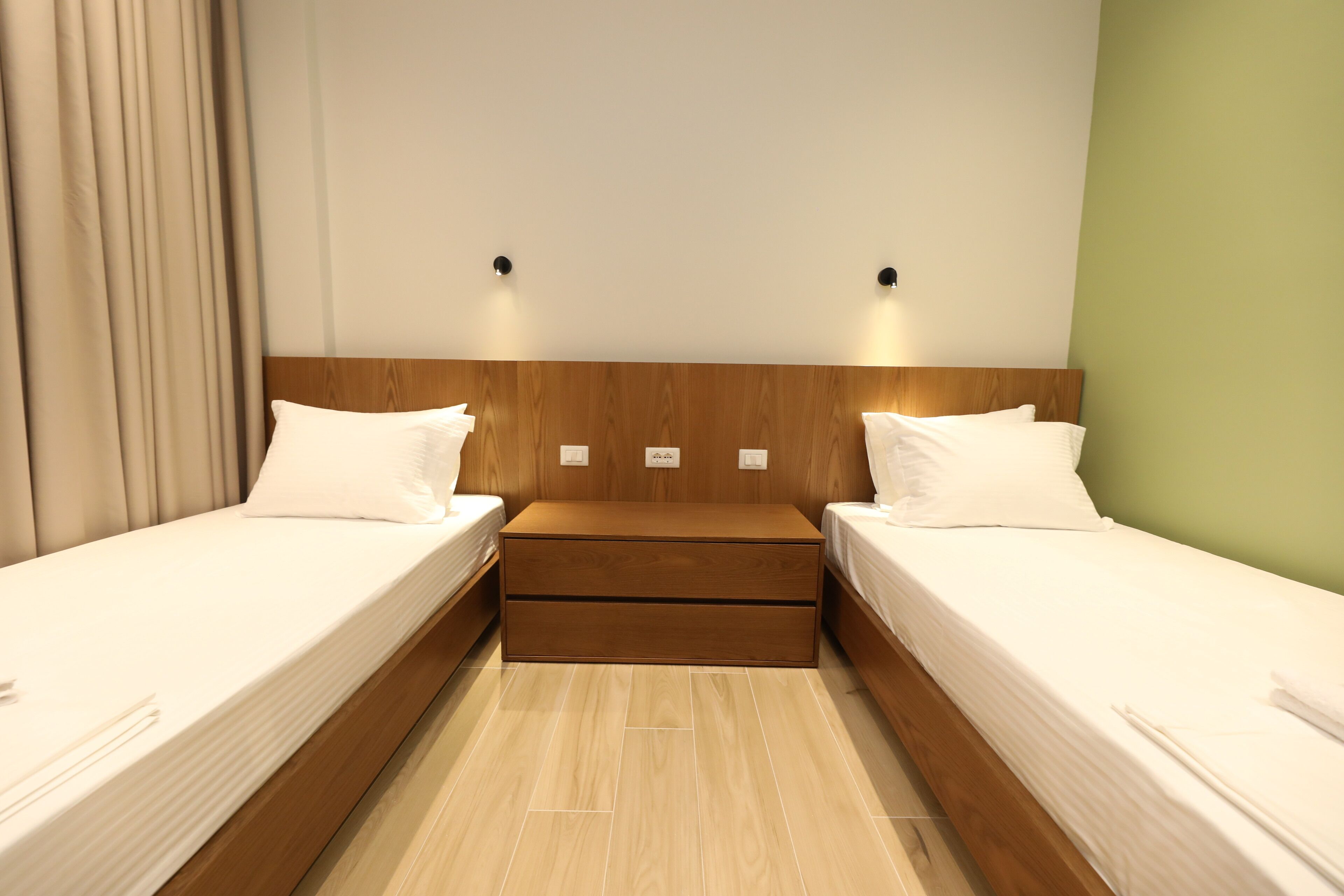 A twin room with two single beds, a wooden headboard, and a small bedside table.