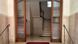 A staircase with a red carpet leading to a wooden door with glass panels. - Ferrhouse 210 Eco & Chic (Firenze)