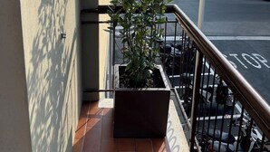 A balcony with a potted plant, a tiled floor, and a view of the street with parked cars and buildings. - Ferrhouse 210 Eco & Chic (Firenze)