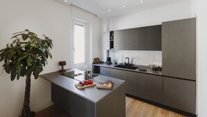 A modern kitchen with a central island, built-in appliances, and a large window. - Ferrhouse 210 Eco & Chic (Firenze)