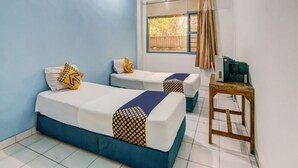 A room with two beds, a small table, and a window with curtains. - Hotel Margadana (Tegal)