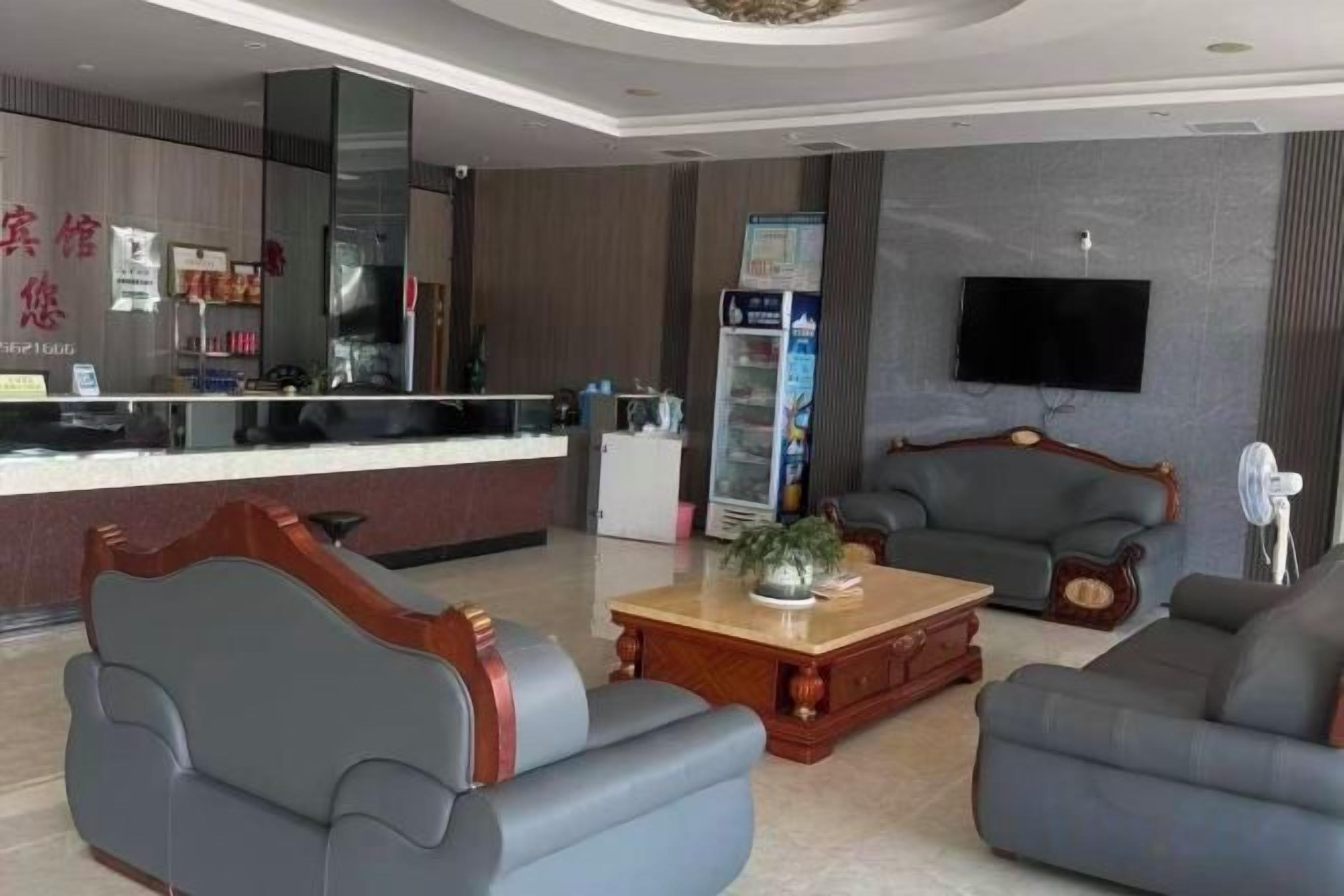 A hotel lobby with a reception desk, seating area, and a flat-screen TV mounted on the wall.
