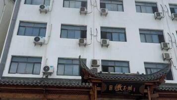 A building with multiple air conditioning units, a traditional Chinese architectural entrance, and a sign with Chinese characters.